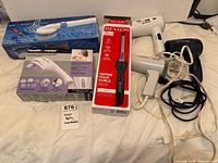Overall view of boxed massagers, curling iron and three hair dryers with cords