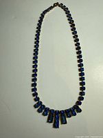 Full view of blue rhinestone bib necklace laid flat