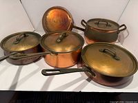 Top view displaying four lidded copper pans and one unlidded pan