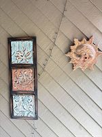 vertical three-tile panel and sun face plaque on wall