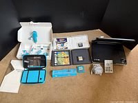Overview showing DSi accessories, game cases, cartridges, Philips DVD player, remote, cables, manuals