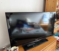 Front view of Samsung TV on stand with remote