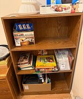 Front view of oak-finish three-shelf bookcase with contents shown for scale