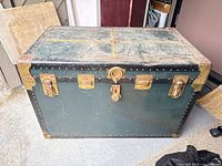 Full view of green steamer trunk with brass hardware