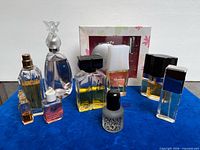 Group shot of eight fragrance items including Anna Sui fairy-topped bottle, boxed Per Una set, multiple rectangular perfume bottles, small perfume oil vial