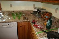 Kitchen counter with green vaseline glass dessert dishes, BBQ utensils, chafing dish, toaster, and bottles