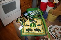 Overview photo showing all John Deere branded items on kitchen counter including trays, dish towel, thermometer, and magnet.