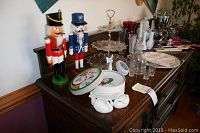 Wide view of nutcrackers, candy dish, vases, plates, decanter and glasses displayed on wood sideboard