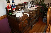 Front and side view of dark wood buffet showing two drawers and two doors with decorative panels and knobs, various small items placed on top not included.
