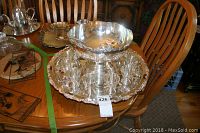 Full set of nickel silver punch bowl, twelve cups on large tray with rose design, on wooden table.