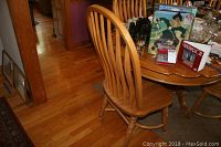 Side view of a single oak dining chair showing spindle back and contoured wooden seat