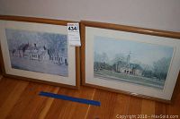Two framed Williamsburg prints side by side on the floor against a wall.