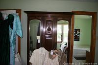 Front view of the three-piece dark wood antique wardrobe with two mirrored doors and central carved panel.