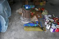 Wide view showing rolled camping chair, fishing rods, tarps, paint cans, and assorted items on floor