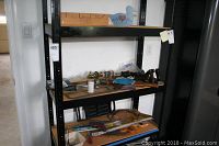 Wide shot of metal shelving unit holding various hand tools including planes, hammers, saws, smaller tools and accessories, some partially boxed, placed on wooden shelves.