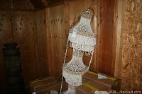 Shell beaded hanging lamp displayed upright with chain, surrounded by cardboard boxes.