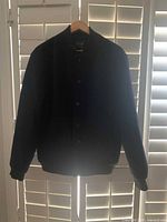 Full front view of navy bomber jacket on hanger