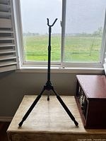 Overall view of black metal tripod guitar stand on table by window