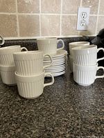 Stacked ceramic ribbed cups and saucers on counter
