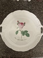 Top view of white porcelain handled platter with rose motif and handles