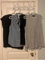 Three sleeveless tops hanging on door