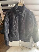 front view of black Reebok quilted jacket on hanger