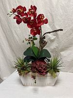 Full view of arrangement showing red orchids, succulents, driftwood and white planter