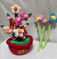 Full view of potted felt flower arrangement beside three smiling face flower stems