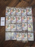 Twenty individually sleeved Pokémon cards arranged in four rows on wood floor; majority show Tornadus full art with some different artwork presumed N’s Zorua