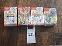 Four sealed booster bundles lined up showing front artwork and set names