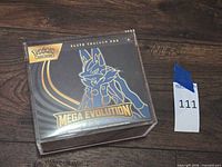 Front of sealed Mega Evolution Elite Trainer Box inside acrylic case
