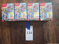 Five Journey Together booster boxes shown on wood floor, lot tag visible