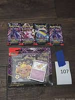 Four sealed Paldean Fates booster packs and sealed Tech Sticker Collection blister displayed together