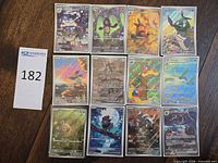 All 12 sleeved Pokémon holo/full-art cards laid out