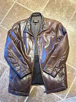 Full view of brown leather jacket front side on tiled floor
