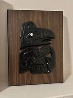 Front view showing black Indigenous style relief on wood panel