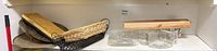 Shelf view showing metal platters, cutting boards, baskets, glass dishes, pitcher, candle box