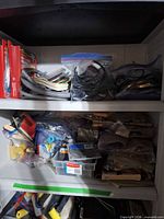 Shelving with weatherstripping rolls, insulation kits, sanding belts, Rubbermaid box with fasteners, cables and cords