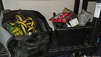 Open grey-black tool bag with tow straps and inflator visible next to black bin of mixed parts