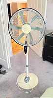 Full view of beige/teal Bionaire pedestal fan with cord and base