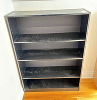 Full view of black five-shelf bookcase against wall
