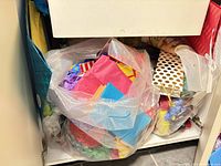 Cabinet view with clear bag of multicolor tissue, striped and polka-dot gift bags