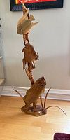 Full view of tall three-fish wood sculpture