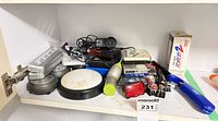 Shelf view showing charger, LED puck and bar lights, pens, clips, lighter and misc items
