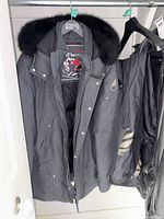 Full view of parka hanging with snow pants adjacent