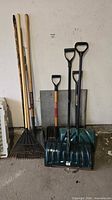 Group view of all long-handled tools leaning against wall