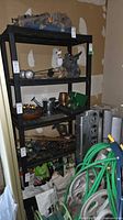 Overall view of black plastic five-shelf unit with items on it