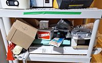 Full view of white and gray plastic 3-shelf unit holding assorted items