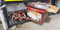 Boxed Sidewind car cover next to pile of SmartStraps ratchet tie-downs showing colours and hooks