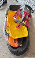 Yellow Pelican Sno Twister sled stacked on steering snow racer and foam sled